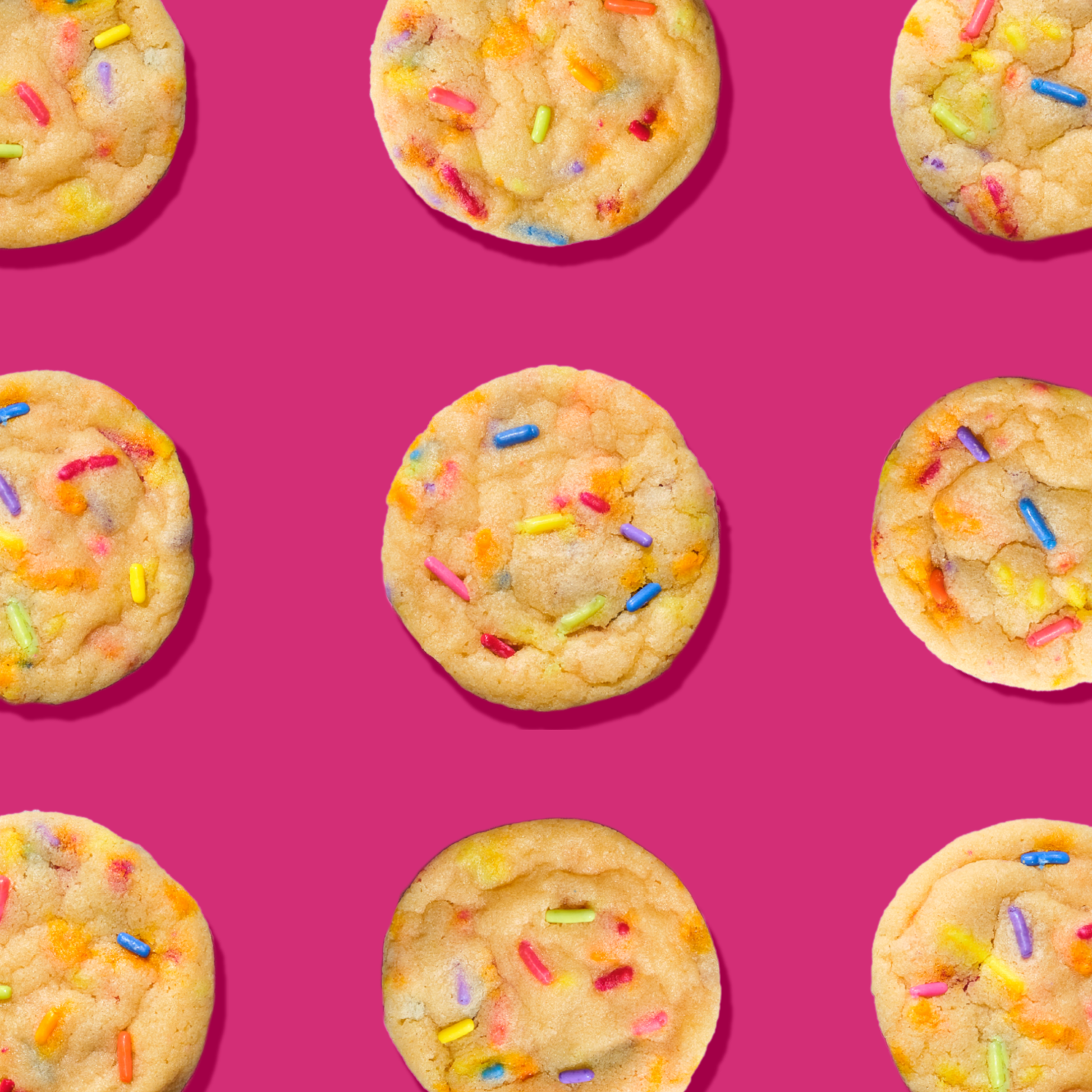 Several cookies with sprinkles on a pink background