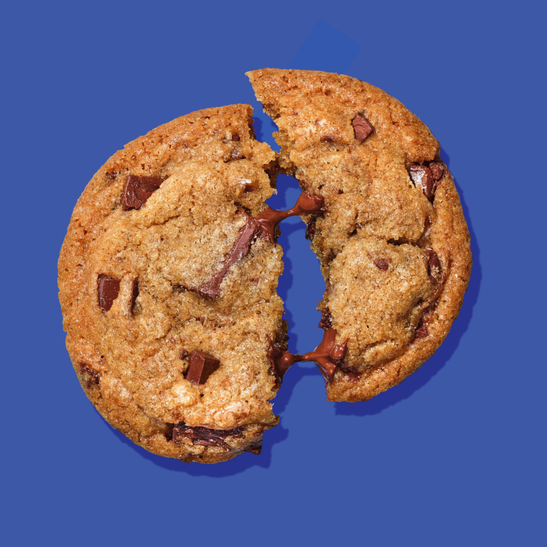 Bakr Brown Butter Chocolate chunk cookie broken in half on a blue background