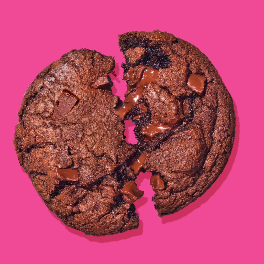 Bakr Fudge Brownie cookie broken in half on pink background